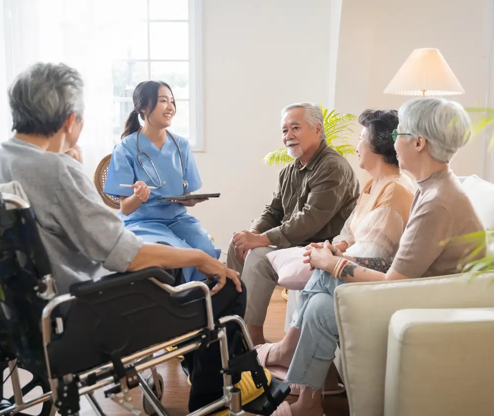 Group of Asian senior people sit in a circle in a nursing home and listen to nurse during a group elderly therapy session
